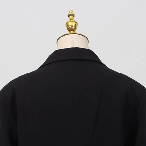 Detailaufnahme des Rückenkragens und der Schulternaht eines schwarzen taillierten Blazers
