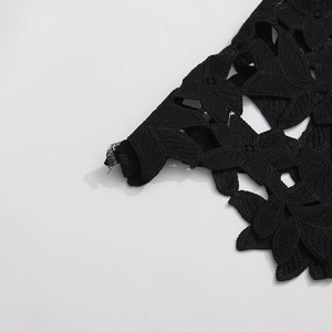 Gros plan sur un tissu en dentelle florale noire avec broderie ajourée en forme de feuille