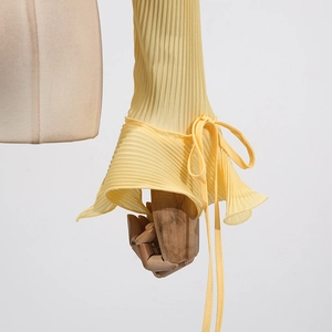 Detail of yellow pleated top featuring flared sleeves and drawstring bow accents