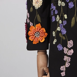 Gros plan détaillé de la broderie florale 3D avec perles et strass sur blazer noir