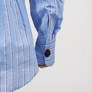 Dettaglio del polsino della camicia a righe blu con bottone gioiello decorativo