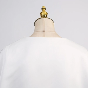 Détail du chemisier en satin blanc avec encolure ronde épurée et coutures de haute précision