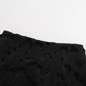 Détail macro d'un tissu noir élégant présentant des motifs floraux ajourés complexes