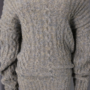 Detailed close-up showing the cable-knit texture and mixed grey-green yarn of the dress