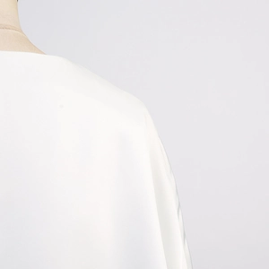 Détails montrant la texture lisse et les coutures d'un chemisier en satin blanc