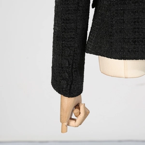 Dettaglio della manica del blazer in tweed nero con bottoni rivestiti in tessuto e trama