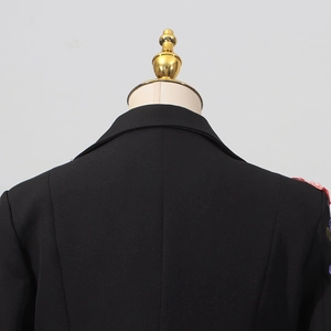 Détail de broderies florales et perles roses sur l'épaule d'un blazer noir élégant