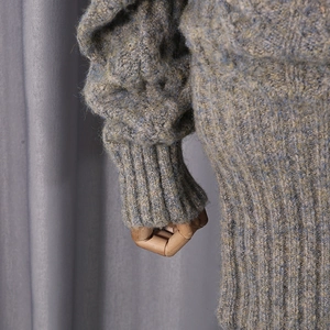 Detail of chunky cable knit dress featuring multi-color mixed yarn and ribbed cuffs