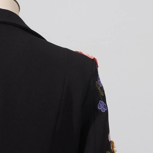 Détail de la broderie florale et des perles sur la manche du blazer noir cintré