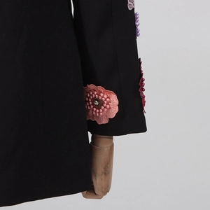 Détail de fleurs brodées en 3D avec perles roses et cristaux sur manche noire