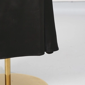 Dettaglio macro dell'orlo della gonna in raso nero che mostra il drappeggio e la finitura