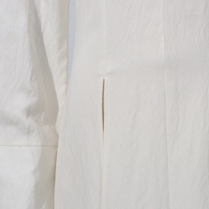 Detailed close-up of high-quality stitching and side slit on a white elegant dress