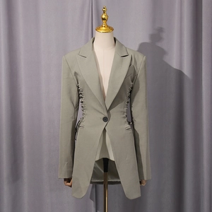 Detail of sage green blazer with metal eyelet lace-up waist and irregular hem design
