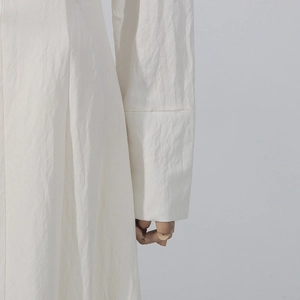Detail of white cotton linen long sleeve cuff and side seam on a wooden mannequin