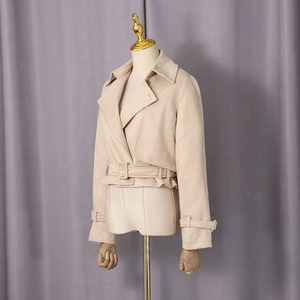 Détail d'une veste courte beige en suédine avec de larges revers et une ceinture réglable