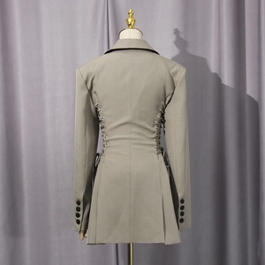 Detail of cross-lace waist design and accordion pleats on the back of a grey blazer
