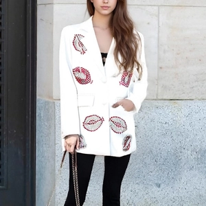 Détail de lèvres en paillettes rouges et argentées sur un blazer blanc mi-long