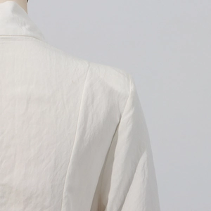 Detail of elegant white slit dress showing textured fabric and fine shoulder stitching