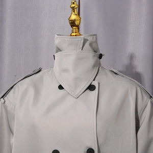 Détail de la veste croisée gris clair montrant le col haut et les pattes d'épaule