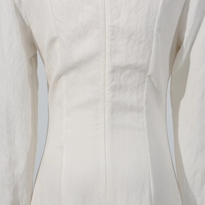 Detailed close-up of vertical waist stitching on a white long-sleeve dress fabric