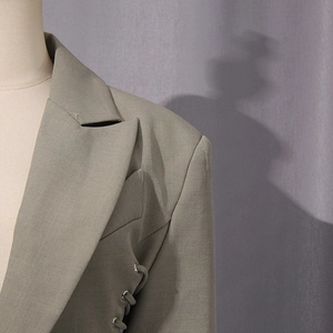 Detailed close-up of taupe suit lapel and shoulder with lace-up side design and eyelets