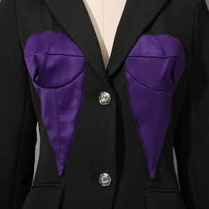 Detail of black blazer featuring a purple satin corset insert and floral silver button