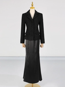 Completo due pezzi da donna con blazer in tweed nero e gonna lunga in raso su manichino