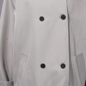 Vue détaillée de la veste croisée bleu-gris avec boutons noirs et poches obliques