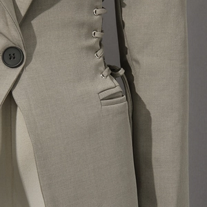 Detail shot of khaki blazer featuring lace-up side design and metallic eyelet accents