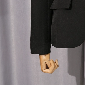 Detail of black blazer showing sleeve cuff and flap pocket on a mannequin model