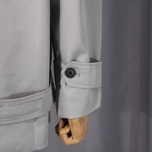 Détail du poignet d'une veste grise avec sangle réglable et bouton noir élégant