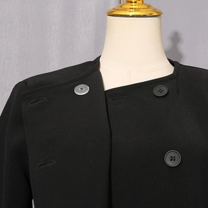Detail of black asymmetric blazer showing buttons and high-density woven fabric texture