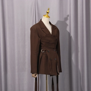 Detail of coffee blazer featuring structured waist layering and elegant side straps