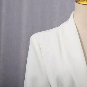 Detailed close-up of shoulder padding and fine twill texture on a white blazer