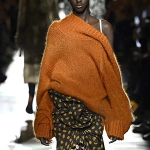 Detail of a bright orange oversized mohair sweater with off-the-shoulder knit design