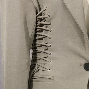 Detailed view of the side lace-up design and metal eyelets on a khaki slim fit blazer