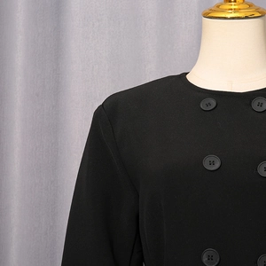 Detail of black double-breasted slim blazer with matte fabric and round neck on mannequin
