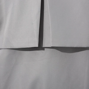 Vue détaillée de la texture du tissu gris et du plissage précis sur la veste