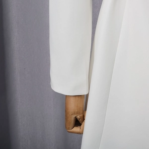 Close-up of white blazer sleeve showing premium diagonal twill fabric texture and stitching