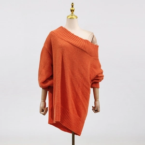 Detailed close-up of orange off-shoulder knit sweater with ribbed cuffs and fuzzy texture