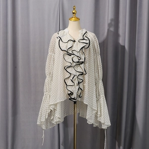 Detail of white polka dot chiffon blouse featuring tiered ruffles and flared sleeves