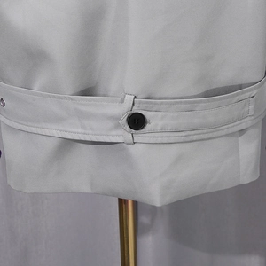 Détail de la ceinture de veste grise avec bouton noir et texture du tissu