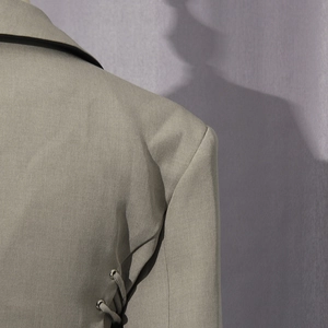 Detail of blazer featuring side metal eyelets and cross lace-up design on twill fabric