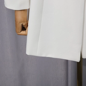 Detailed close-up of white blazer twill fabric texture and tailored hem on mannequin