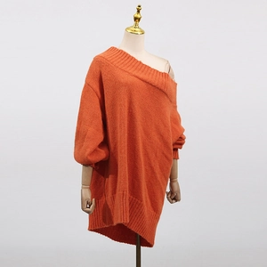 Detailed knit texture of oversized orange off-shoulder sweater with ribbed edges