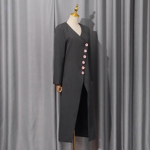 Detailed view of dark grey blazer featuring elegant pink floral decorative buttons on front