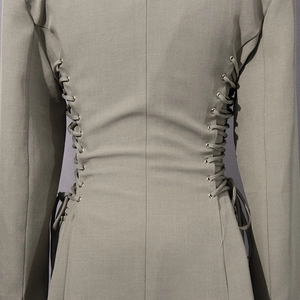 Detailed close-up of side metal grommets and lace-up waist design on a slim-fit blazer