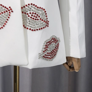 Détail de lèvres en strass rouges et argentés sur le bas d'un blazer blanc