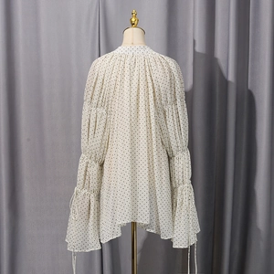 Close-up of lantern sleeves with ruffles and ribbons on a polka dot chiffon shirt