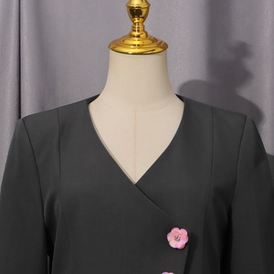 Detail of dark grey V-neck blazer featuring decorative pink sequin flower buttons